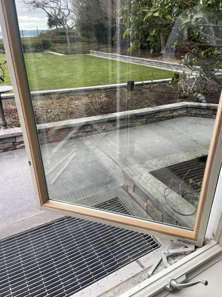 A restored Pella casement window open to a garden