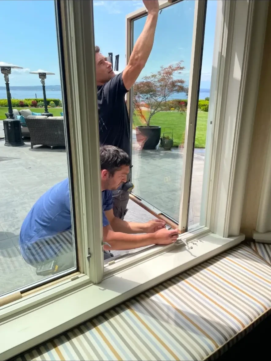 Restoration technicians fitting a restored wood casement sash in an oceanfront home